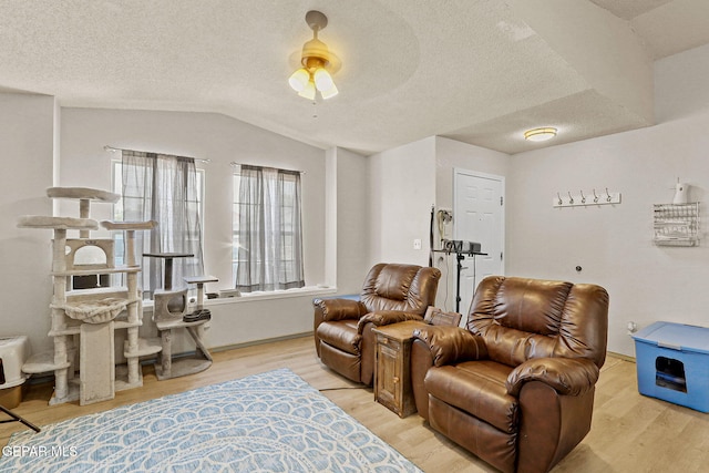 interior space featuring vaulted ceiling, ceiling fan, a textured ceiling, and light wood-style flooring