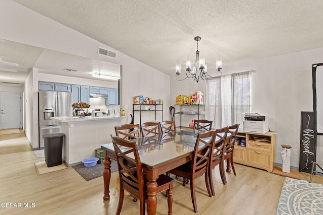 dining space featuring vaulted ceiling, an inviting chandelier, visible vents, and light wood-style floors