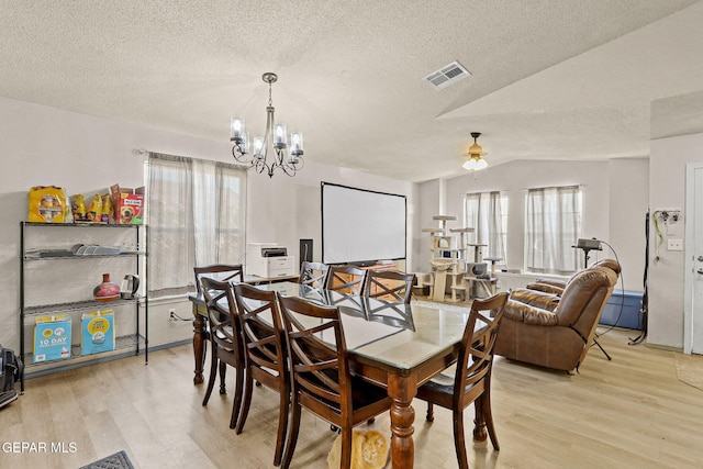 dining room featuring light wood-style flooring, visible vents, and a textured ceiling