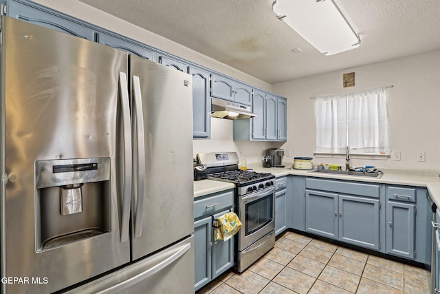 kitchen with light tile patterned floors, stainless steel appliances, light countertops, under cabinet range hood, and a sink