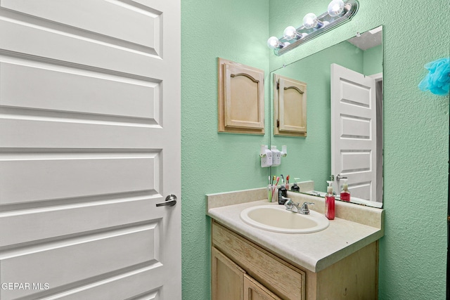 bathroom with a textured wall and vanity