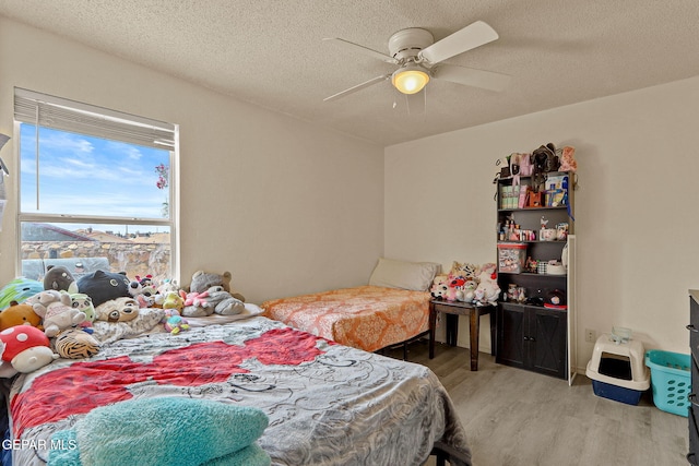 bedroom with ceiling fan, a textured ceiling, and wood finished floors