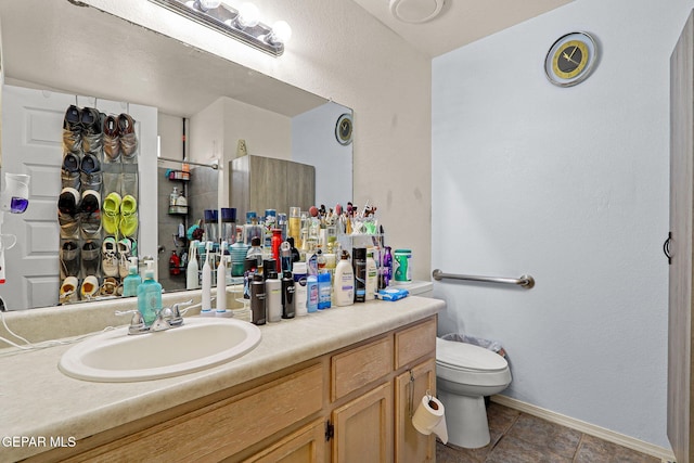 bathroom with baseboards, vanity, toilet, and tile patterned floors