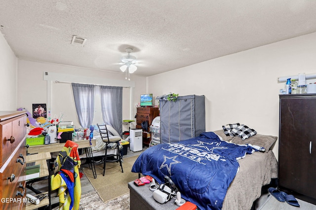 bedroom featuring a textured ceiling, carpet, visible vents, and a ceiling fan