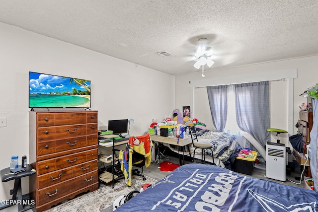 bedroom featuring a textured ceiling, visible vents, and a ceiling fan