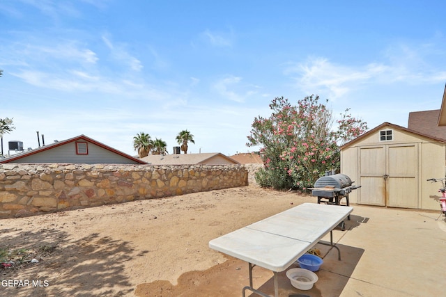 view of yard featuring an outbuilding, a patio area, fence, and a storage unit