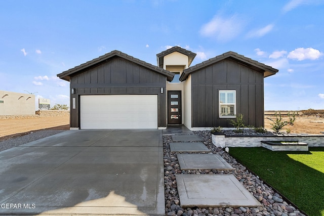 view of front of property with driveway, a tile roof, a garage, and board and batten siding