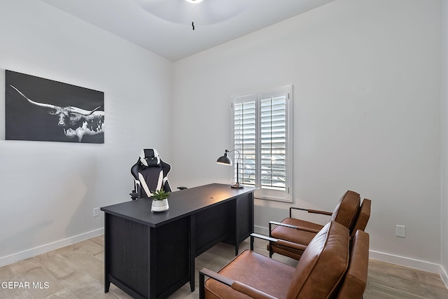 office space with light wood-style floors, a ceiling fan, and baseboards