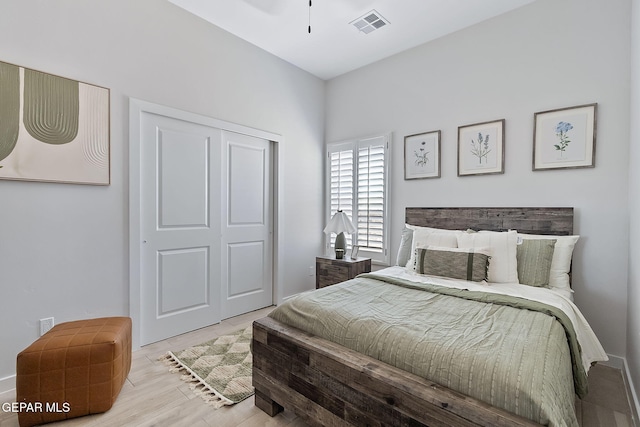 bedroom featuring light wood finished floors, visible vents, and a closet