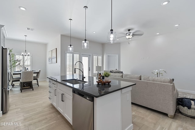 kitchen with visible vents, appliances with stainless steel finishes, open floor plan, white cabinetry, and a sink