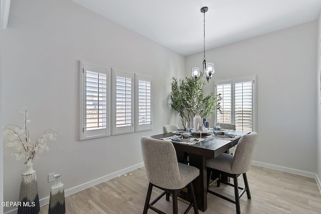 dining space with light wood-type flooring, baseboards, and an inviting chandelier