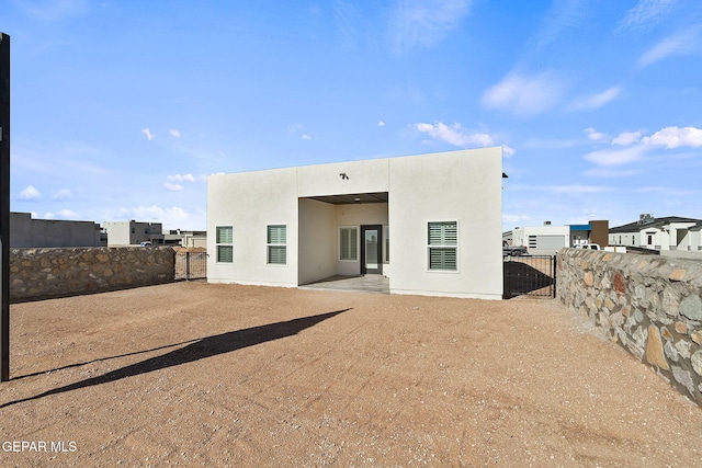 back of property with a gate, fence, a patio, and stucco siding