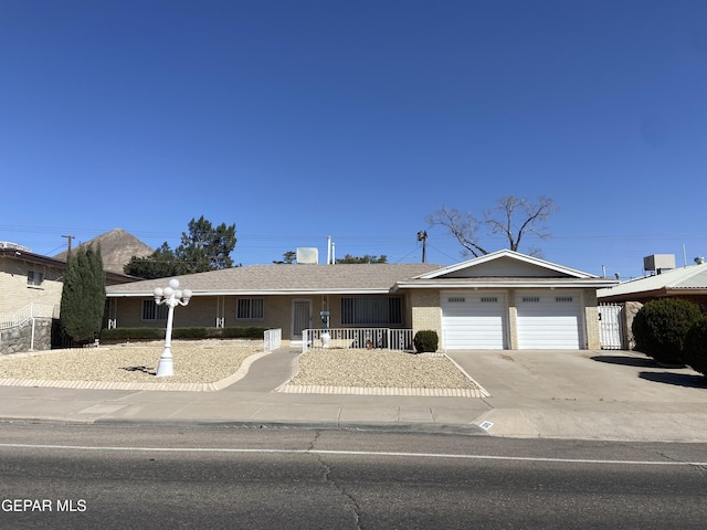 single story home with a porch, brick siding, driveway, and an attached garage