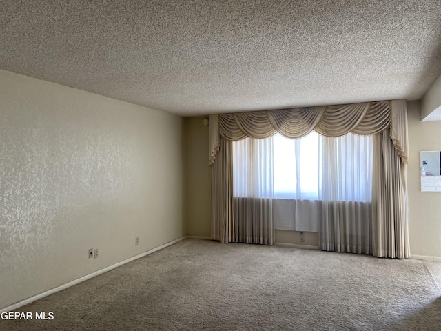 empty room featuring a textured ceiling, carpet flooring, and a textured wall