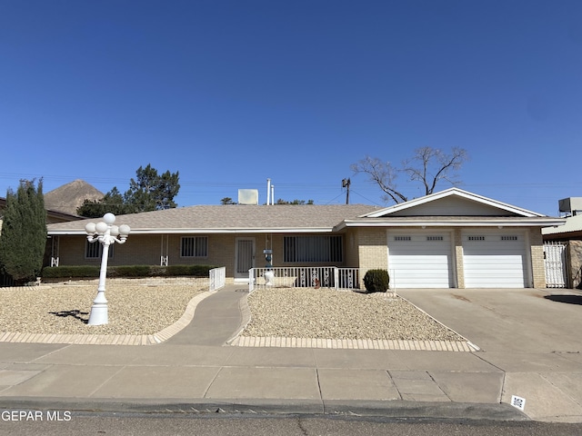 ranch-style home featuring brick siding, a shingled roof, concrete driveway, covered porch, and a garage