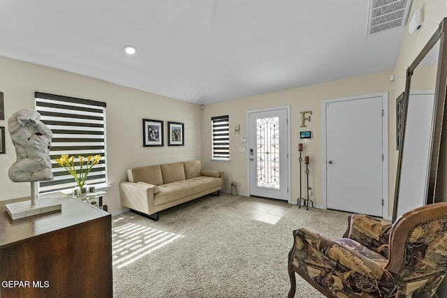 carpeted living room with visible vents, baseboards, and tile patterned flooring