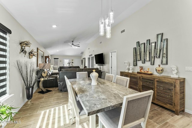 dining space with wood finish floors, visible vents, a ceiling fan, baseboards, and vaulted ceiling