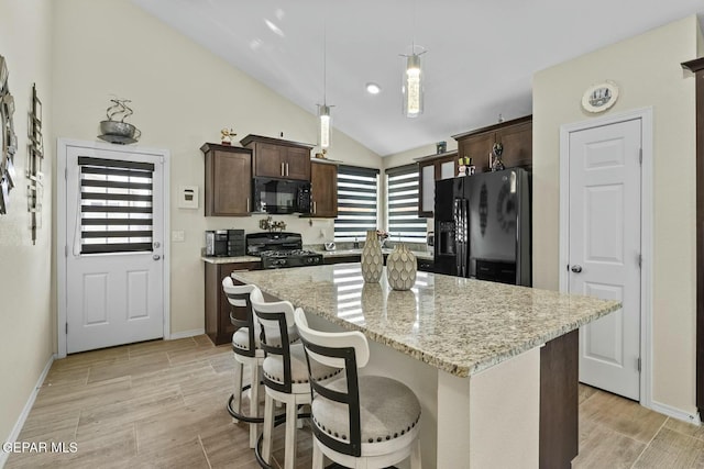 kitchen featuring a center island, dark brown cabinets, black appliances, and decorative light fixtures