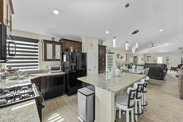 kitchen featuring dark brown cabinets, a center island, a toaster, black appliances, and a sink