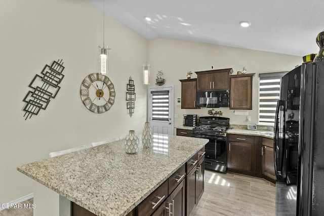 kitchen with a center island, light stone countertops, dark brown cabinetry, vaulted ceiling, and black appliances