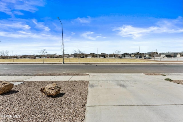 view of road with a residential view, street lighting, and sidewalks