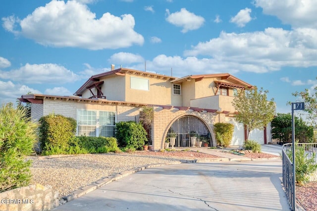 mediterranean / spanish home with a garage, concrete driveway, brick siding, and stucco siding