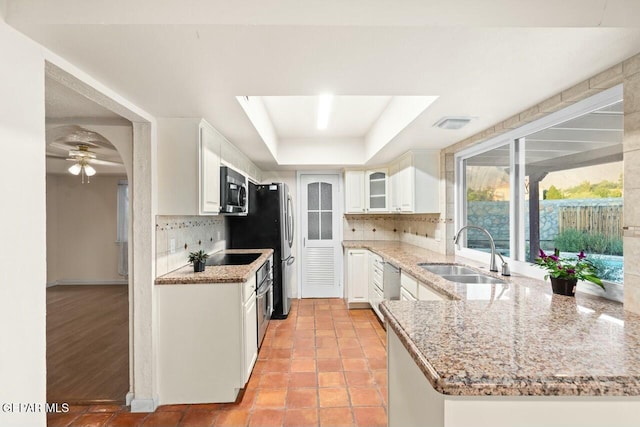 kitchen with white cabinets, appliances with stainless steel finishes, a raised ceiling, and a sink