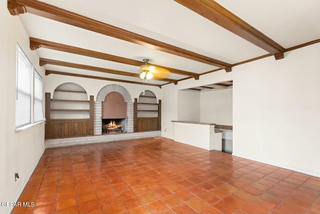 unfurnished living room featuring ceiling fan, a fireplace, beam ceiling, and built in features