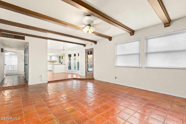 unfurnished living room featuring light tile patterned floors, visible vents, arched walkways, a ceiling fan, and beamed ceiling