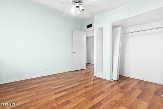 unfurnished bedroom featuring a ceiling fan, a closet, visible vents, and wood finished floors