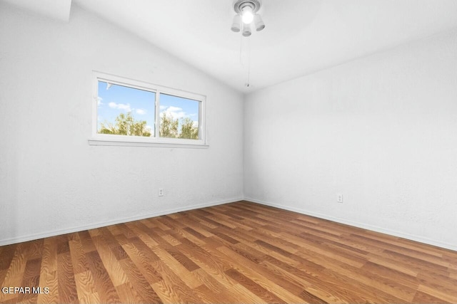 empty room featuring baseboards, vaulted ceiling, and wood finished floors