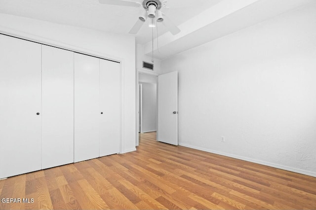 unfurnished bedroom featuring visible vents, a ceiling fan, vaulted ceiling, a closet, and light wood finished floors