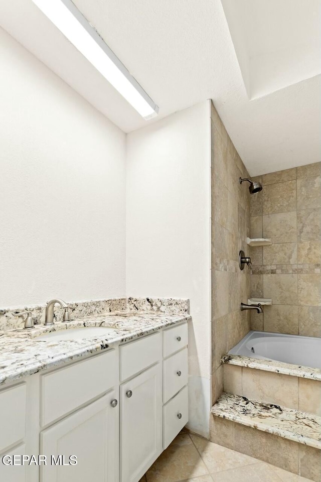 bathroom with tiled shower / bath combo, tile patterned flooring, and vanity