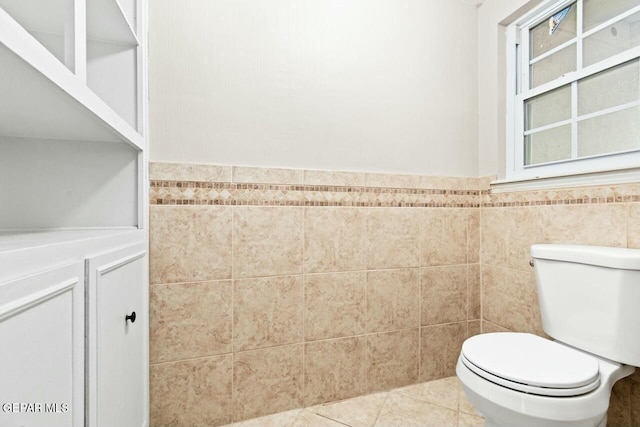 bathroom with wainscoting, tile patterned floors, toilet, and tile walls