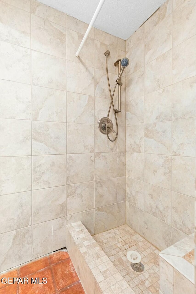 full bath with a textured ceiling and tiled shower