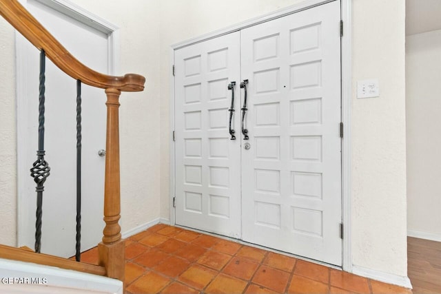 entryway with stairs, baseboards, and tile patterned floors