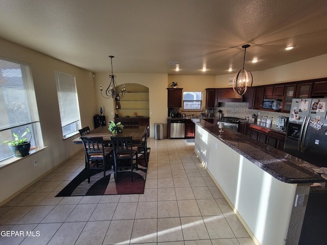 kitchen with an inviting chandelier, tasteful backsplash, stainless steel appliances, and light tile patterned flooring