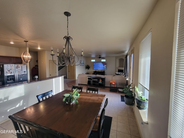 dining area with ceiling fan with notable chandelier and light tile patterned floors