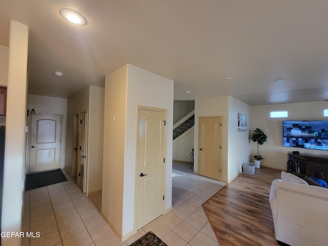 hallway featuring light tile patterned flooring and stairway