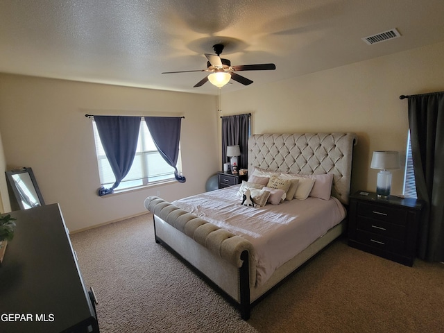 carpeted bedroom with ceiling fan, visible vents, and a textured ceiling