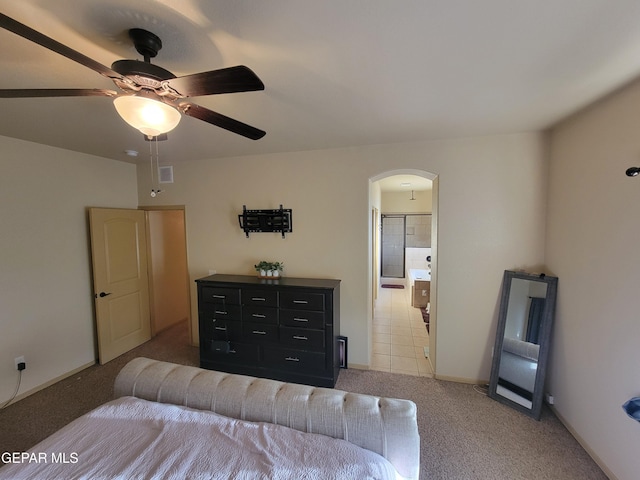 bedroom featuring arched walkways, light colored carpet, visible vents, ceiling fan, and ensuite bath