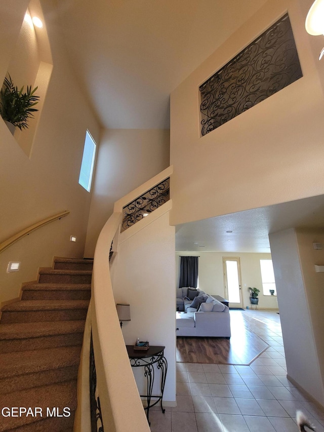 staircase with a towering ceiling and tile patterned floors