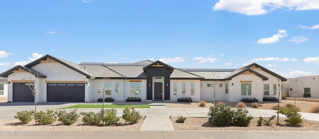 view of front facade with roof mounted solar panels, stucco siding, an attached garage, and driveway