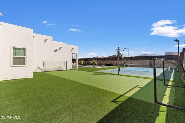 view of sport court featuring a tennis court and fence