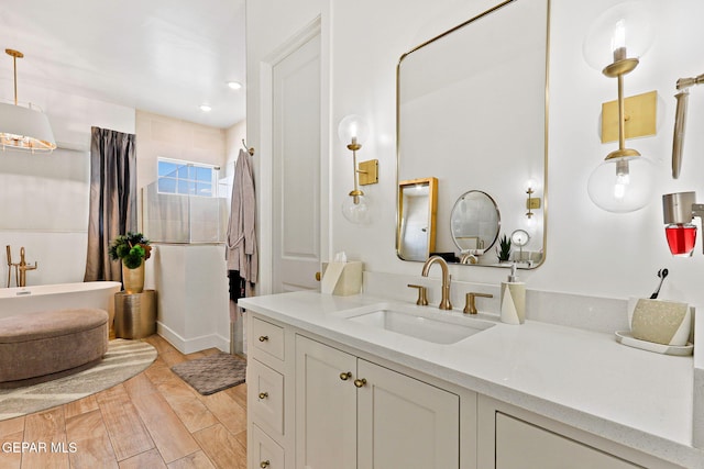 full bath with a soaking tub, vanity, and wood finished floors