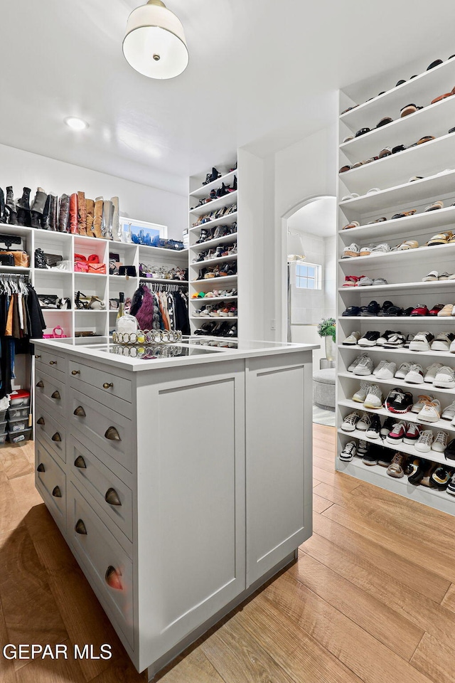 spacious closet featuring arched walkways and light wood finished floors