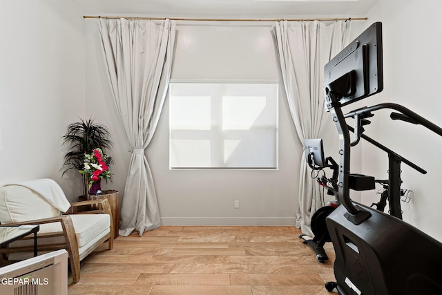 workout room with light wood-type flooring and baseboards