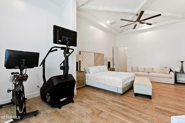 bedroom featuring baseboards, ceiling fan, beam ceiling, light wood-style flooring, and a high ceiling