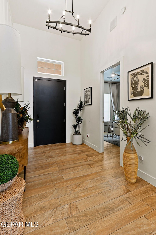 entrance foyer featuring baseboards, visible vents, rail lighting, a towering ceiling, and light wood-type flooring