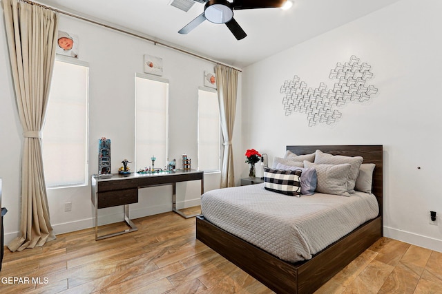 bedroom with light wood finished floors, a ceiling fan, and baseboards